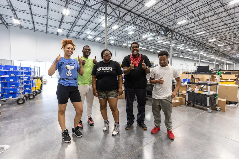 WeShip team members in a warehouse posing for a photo.