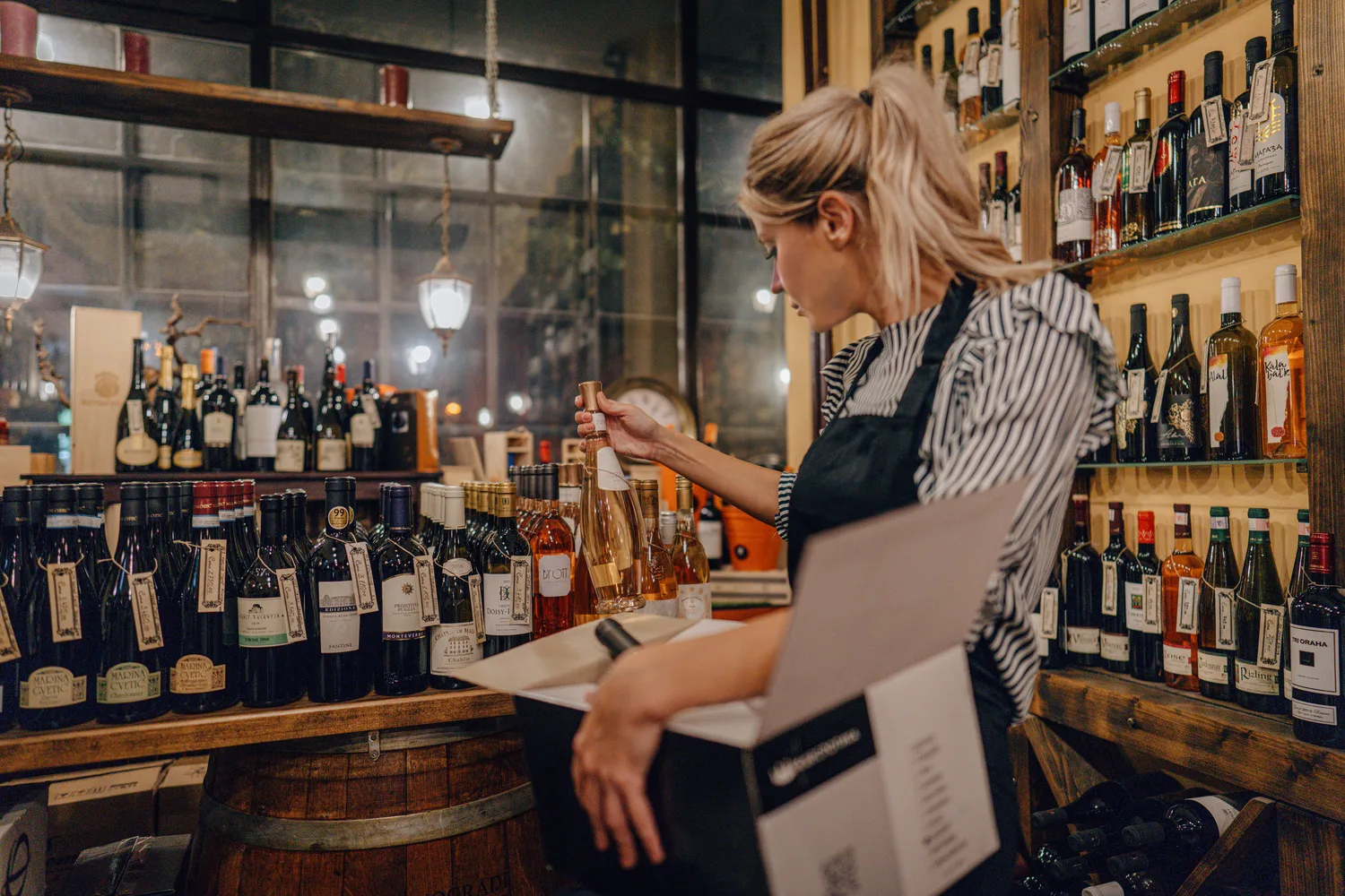 Women packing a box of wine in a wine shop surrounded by bottles of wine